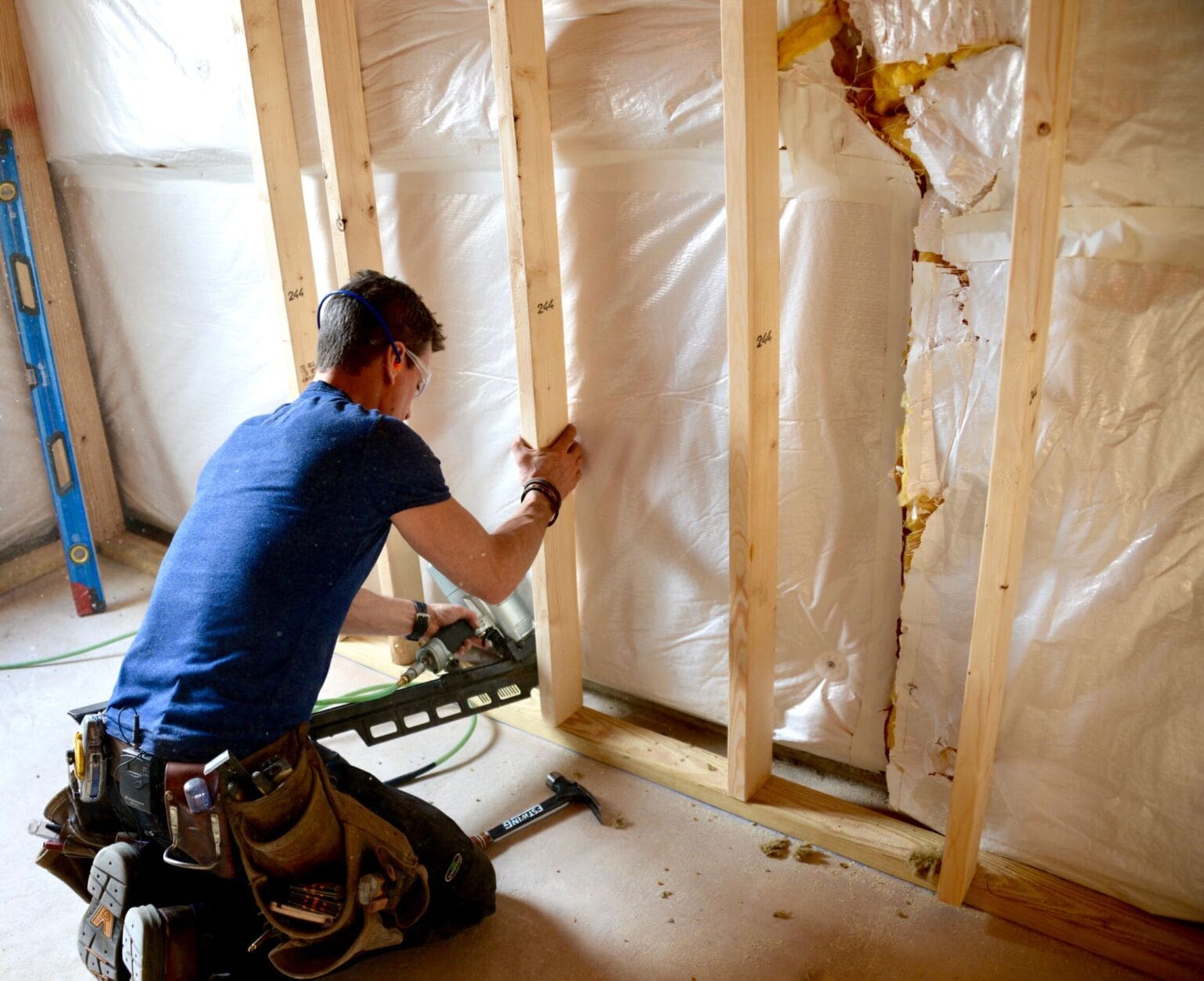 Worker framing studs on partially completed basement