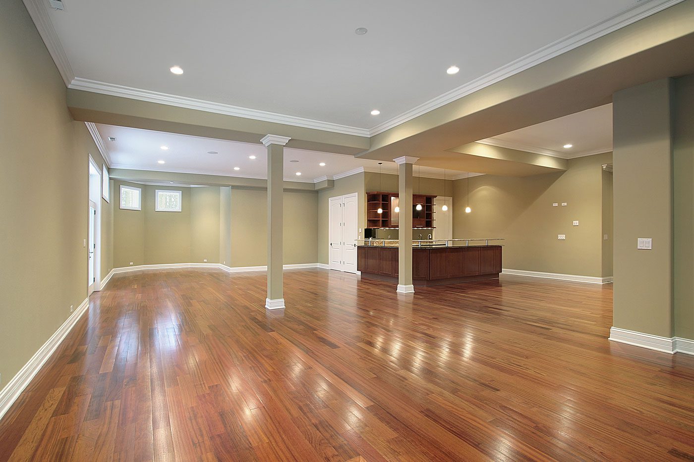 Newly finished basement with clean walls, columns, and hardwood floors.